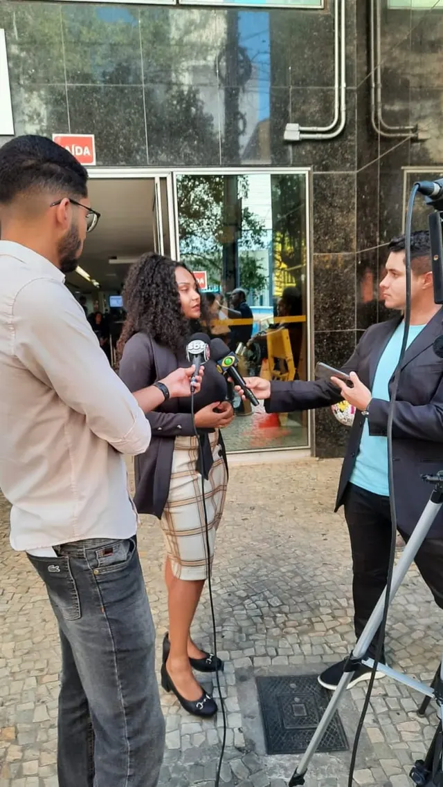 Advogada Criminalista Bruna Vitebro concedendo entrevista a equipes de reportagem em frente a um prédio de Belo Horizonte
